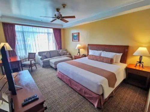 a bedroom with a large bed and a living room at Private Rooms and Cabins in Camp John Hay Baguio in Baguio