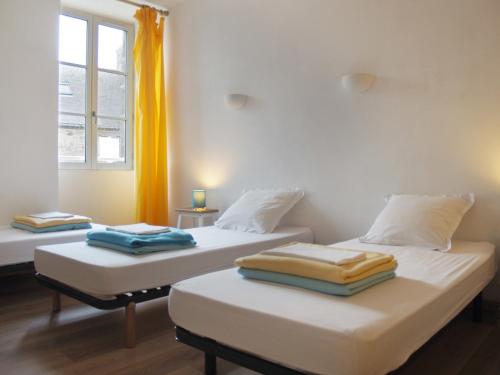 2 łóżka pojedyncze w pokoju z oknem w obiekcie Gîte Les Pingouins de l'Aber w mieście Brélès