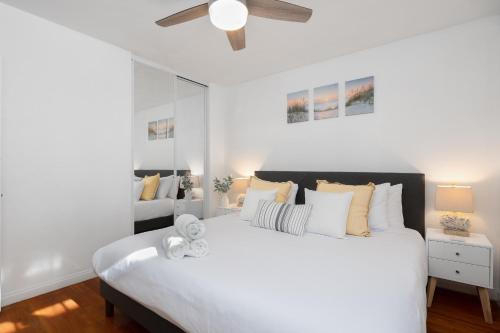 a bedroom with a large white bed with a ceiling fan at 2 Bedroom - Ocean View Hot Tub Parking - 8 Guest in San Diego