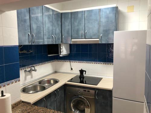 eine kleine Küche mit blauen Schränken und einem Waschbecken in der Unterkunft Apartamento con vistas al mar, Punta Umbria in Punta Umbría