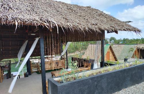 a hut with a straw roof and a table at Riu del Mar Hostel in Dauis