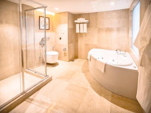 a bathroom with a tub and a shower and a sink at Holiday Inn Dhaka City Centre by IHG in Dhaka