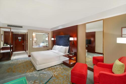a bedroom with a white bed and two red chairs at Holiday Inn Dhaka City Centre by IHG in Dhaka