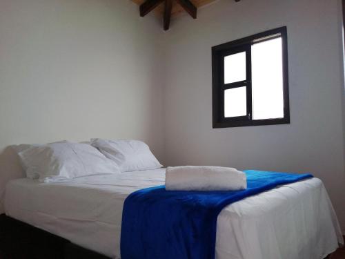 a bedroom with a bed with a blue blanket on it at FINCA LA ALDEA Cabañas campestres in La Tortuga