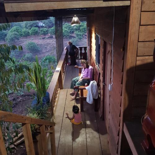 a group of people sitting on the porch of a house at Banlung Mountain View Treks & Tours in Banlung