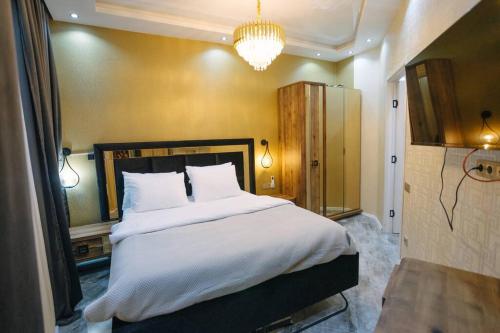une chambre avec un grand lit blanc avec un lustre dans l'établissement Steps Batumi - One Bedroom corner unit ocean view, à Batoumi