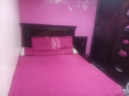a pink bedroom with a bed with pink sheets and pillows at شقه مفروشه فرش فندقي بمدينه العبور الحي الراقي فيو حديقه in ‘Ezbet el-Insha