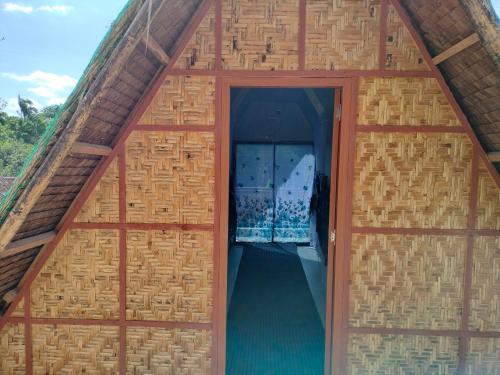 an open door of a bamboo house with a doorway at Riu del Mar Hostel in Dauis