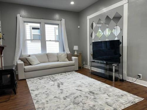 a living room with a white couch and a television at Spacious Downtown Home SJ in San Jose