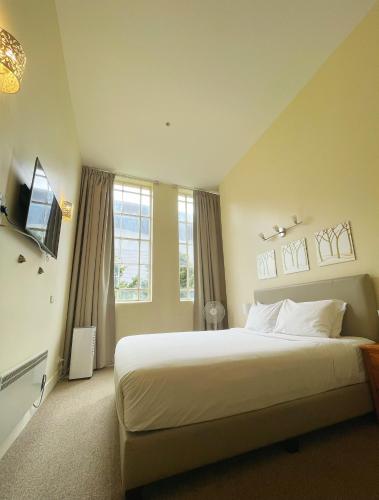 a bedroom with a large white bed and windows at Grand Central Serviced Apartments in Auckland