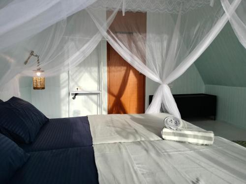 ein Schlafzimmer mit einem weißen Bett mit Baldachin in der Unterkunft Riu del Mar Hostel in Dauis