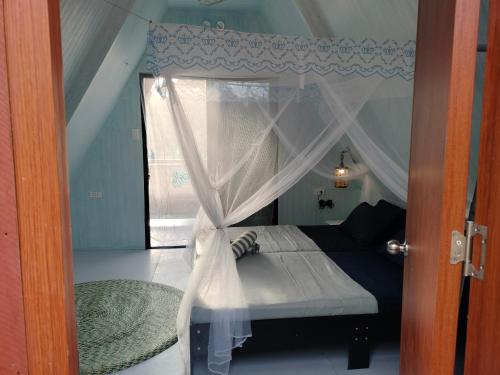 a bedroom with a canopy bed with a window at Riu del Mar Hostel in Dauis