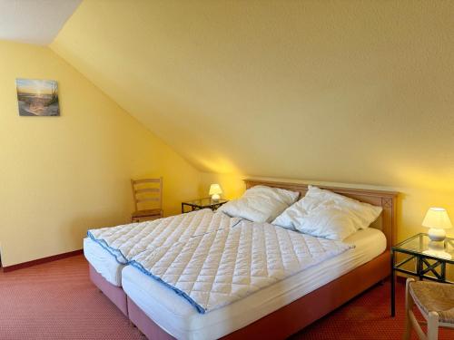 een slaapkamer met een bed met witte lakens en kussens bij Neddesitz - Fewo - 30 - Block in Sagard