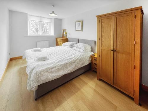 a bedroom with a bed and a wooden cabinet at Castleriggs Cottage - Uk45178 in Threlkeld