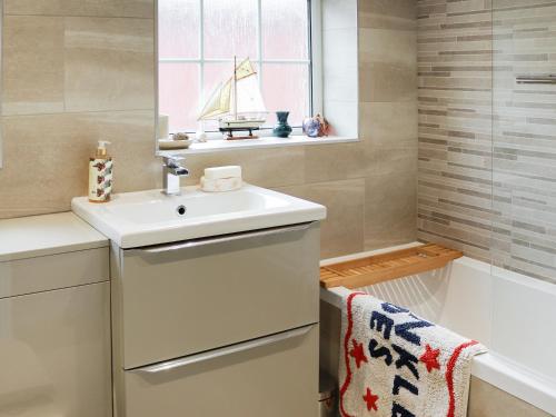 uma casa de banho com um lavatório e uma janela com um veleiro em The Moorings em Rhyl