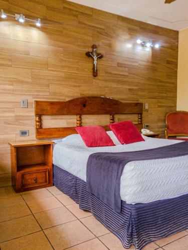 a bedroom with a large bed with red pillows at Hotel Posada Santa Fe Sabinas in Sabinas