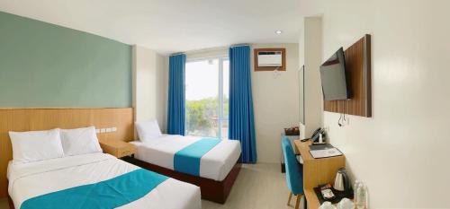 a hotel room with two beds and a television at JRP Vanyard Resort Hotel in Kalibo