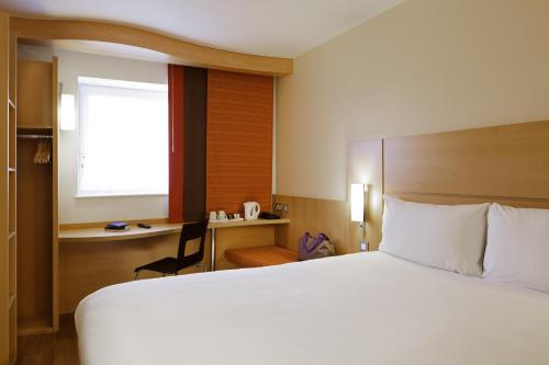 a hotel room with a large bed and a desk at ibis London Shepherds Bush - Hammersmith in London