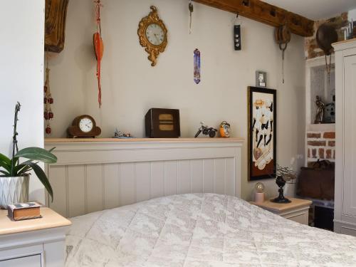 a bedroom with a bed and clocks on the wall at Bramley Cottage in Langley