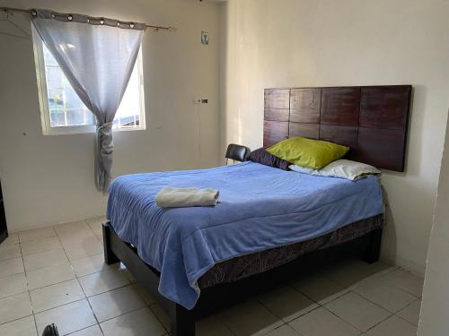 - une chambre avec un lit doté d'une couverture bleue et d'une fenêtre dans l'établissement Habitación privada Leonera, à Cholula