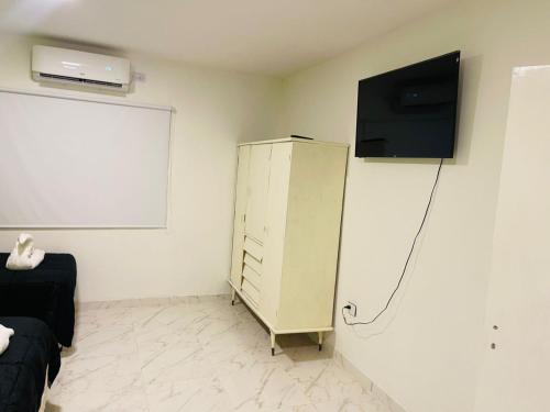 Habitación con armario blanco y TV en la pared. en departamentos Santino en Tinogasta