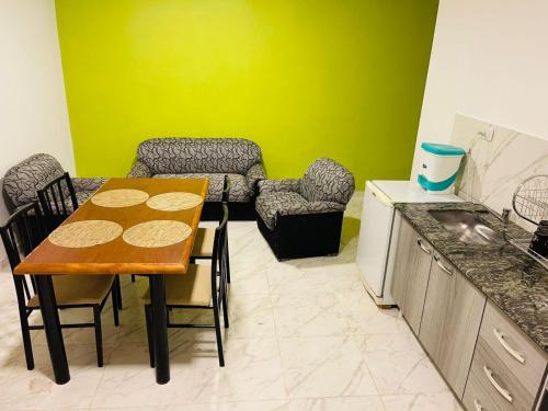 una cocina con mesa y sillas y una cocina con paredes verdes. en departamentos Santino en Tinogasta