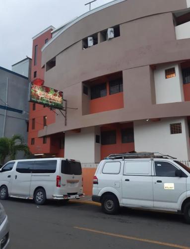 dos furgonetas blancas estacionadas frente a un edificio en Casa hotel apartamento en Santiago de los Caballeros