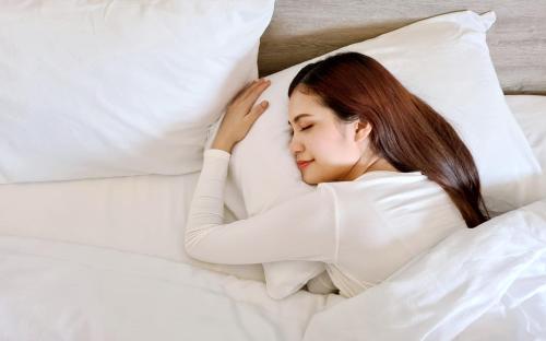 a woman laying in bed with her head on a pillow at Hop Inn Hotel North EDSA Quezon City in Manila