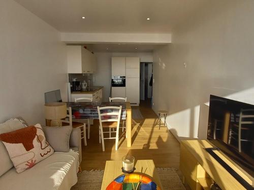 un salon avec un canapé, une table et une cuisine dans l'établissement Appartement moderne 2 chambres, 2 salles d'eau, face mer, parking, proche commerces, St Jean de Monts - FR-1-323-276, à Saint-Jean-de-Monts