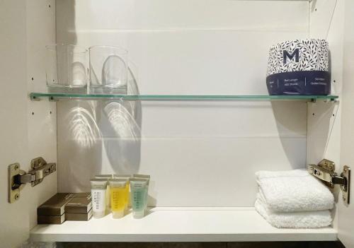 a shelf with glasses and other items in a bathroom at Grand Central Serviced Apartments in Auckland