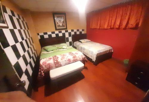 two beds in a room with red walls at HOSTAL CALIFORNIA STAR QUITO in Quito
