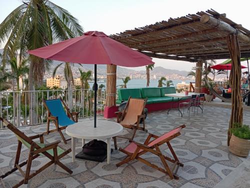 a patio with chairs and a table with an umbrella at Casa Breizh in Acapulco