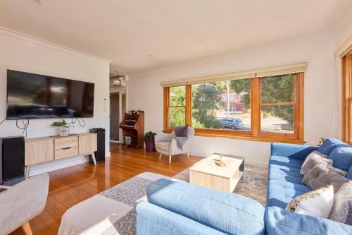a living room with a blue couch and a tv at Basin Road Guesthouse in Royal Park