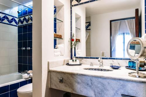 a bathroom with a sink and a toilet and a mirror at Quinta Real Oaxaca in Oaxaca City