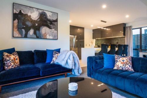a living room with blue couches and a table at Villa Lusso - unwind in luxury and relax in the hot tub in Queenstown