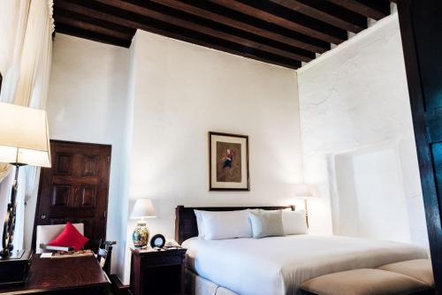 a bedroom with a bed and a desk with a lamp at Quinta Real Oaxaca in Oaxaca City