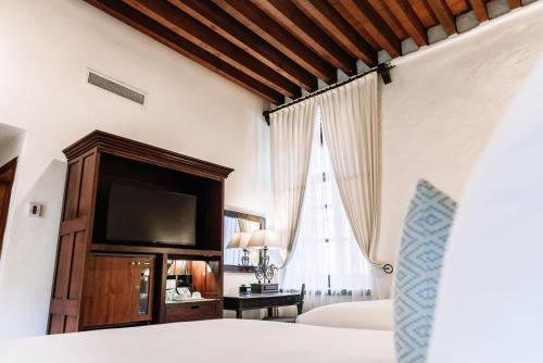 a bedroom with a bed and a flat screen tv at Quinta Real Oaxaca in Oaxaca City