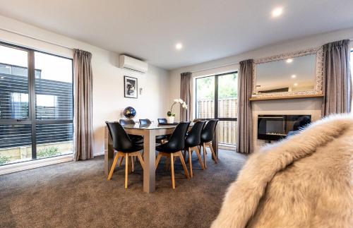 a dining room with a table and chairs and a fireplace at Villa Lusso - unwind in luxury and relax in the hot tub in Queenstown