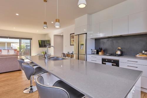 a kitchen with a large counter with chairs in it at The Gorge Townhouse, stunning home & location! in Royal Park