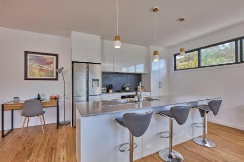 a kitchen with stainless steel appliances and a counter with bar stools at The Gorge Townhouse, stunning home & location! in Royal Park