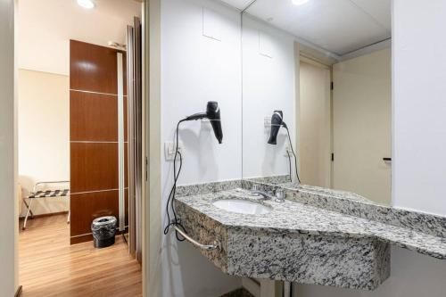 a bathroom with a granite sink and a shower at Flat confortavel com cozinha, e piscina in Osasco