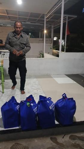 Um homem está ao lado de quatro sacos azuis. em Ifrazim home peninggilan em Bulak