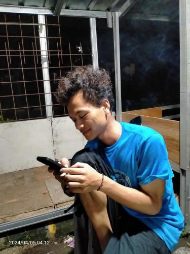 Un jeune homme regarde son téléphone portable dans l'établissement Ifrazim home peninggilan, à Bulak
