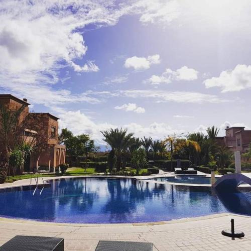 ein großer blauer Pool mit Palmen und Gebäuden in der Unterkunft Villa nova Marrakech in Srarhna
