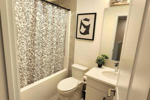 y baño con aseo y cortina de ducha. en Modern entire 3 bedroom home in downtown Edmonton, en Edmonton