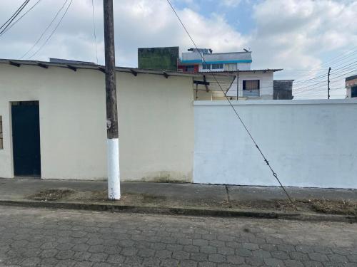 a white building with a pole next to a street at Pikupa in Santo Domingo de los Colorados