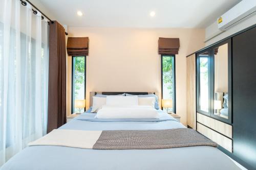 a bedroom with a large bed and two windows at Baan Promphan Premium in Phuket