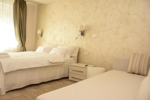 - une chambre blanche avec 2 lits et une chaise dans l'établissement Apartment Venera A&M, à Šabac