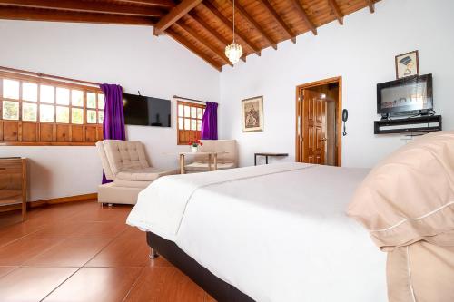 1 dormitorio con 1 cama blanca grande y TV en Hotel Gran Boutique Sabana, en Chía