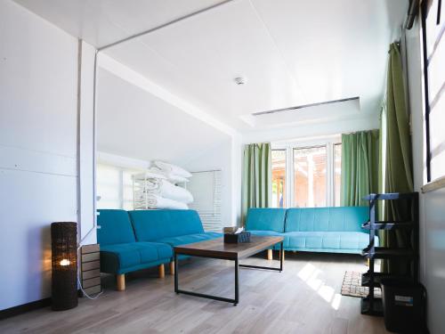 a living room with blue couches and a table at BULLsキャンプ 富士の麓 自然に囲まれたペットと泊まれるゲストハウス Guesthouse with pets at the foot of World Heritage Mt Fuji in Fujikawaguchiko